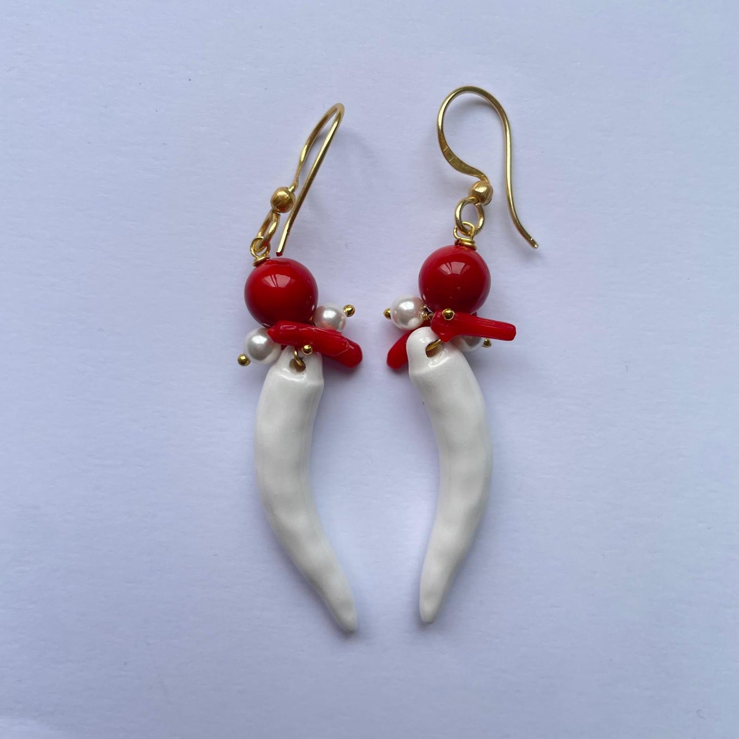 Pendientes de cerámica hechos a mano. El cuerno napolitano es de color rojo, con perla natural de río y coral de Marardi