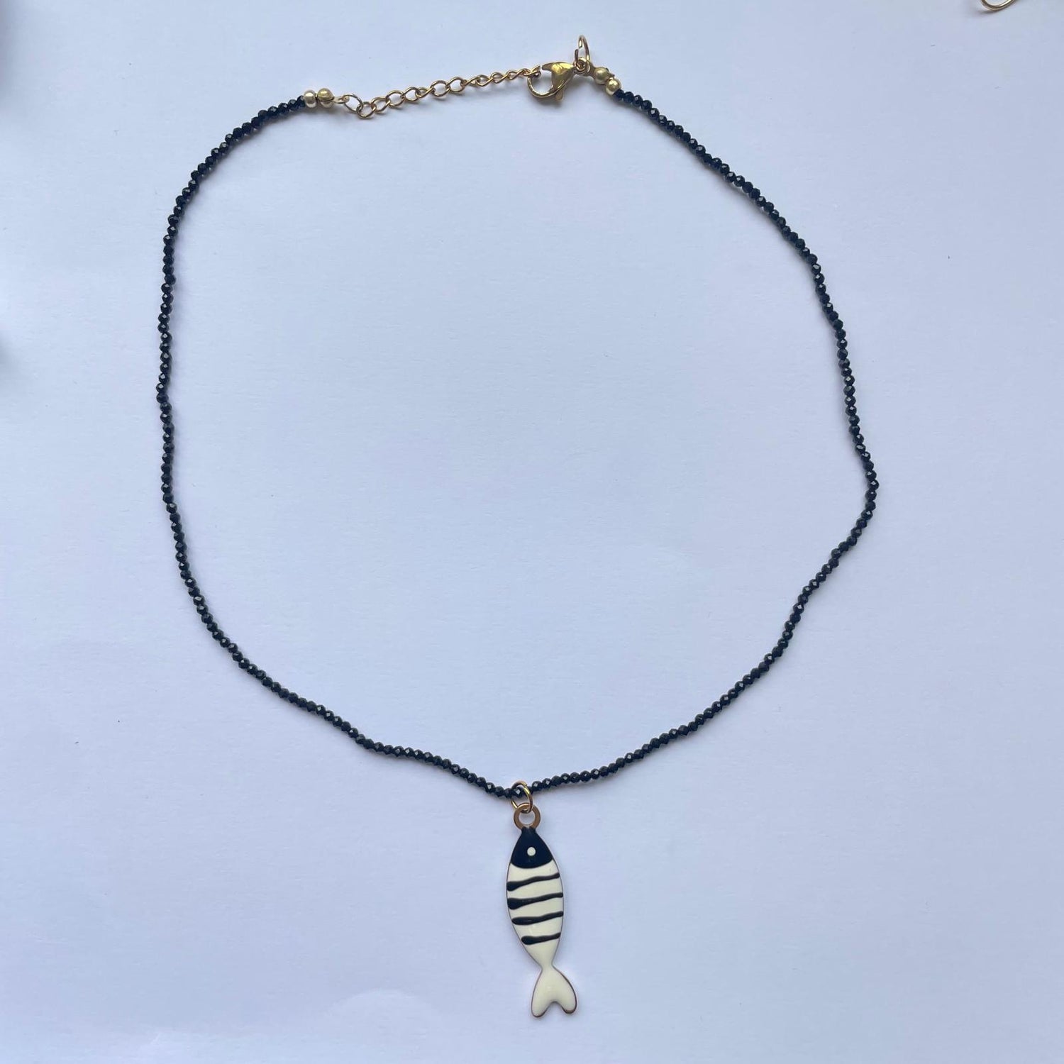 Collar corto compuesto por cadena dorada y cuentas azules y un pez con rayas horizontales azules y blancas de Marardi.