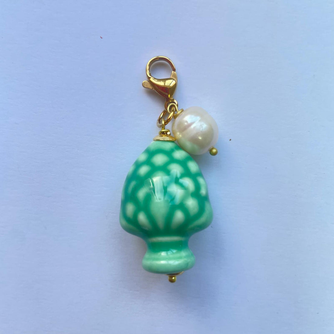Charm de cerámica siciliana que es una piña verde adornada con una perla natural de Marardi.