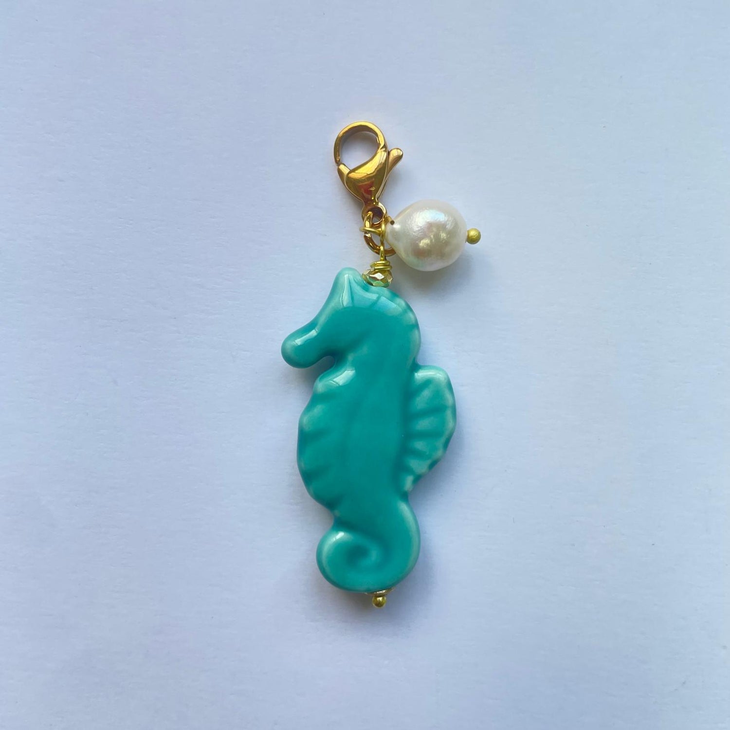 Charm caballito de mar turquesa de cerámica silciliana, hecho y pintado a mano y adornado con una perla natural de Marardi