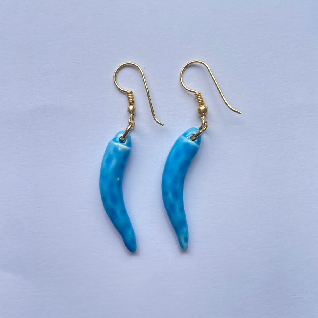 Pendientes de cerámica hechos a mano. El clásico cuerno napolitano es de color azul claro y su gancho de latón de Marardi.