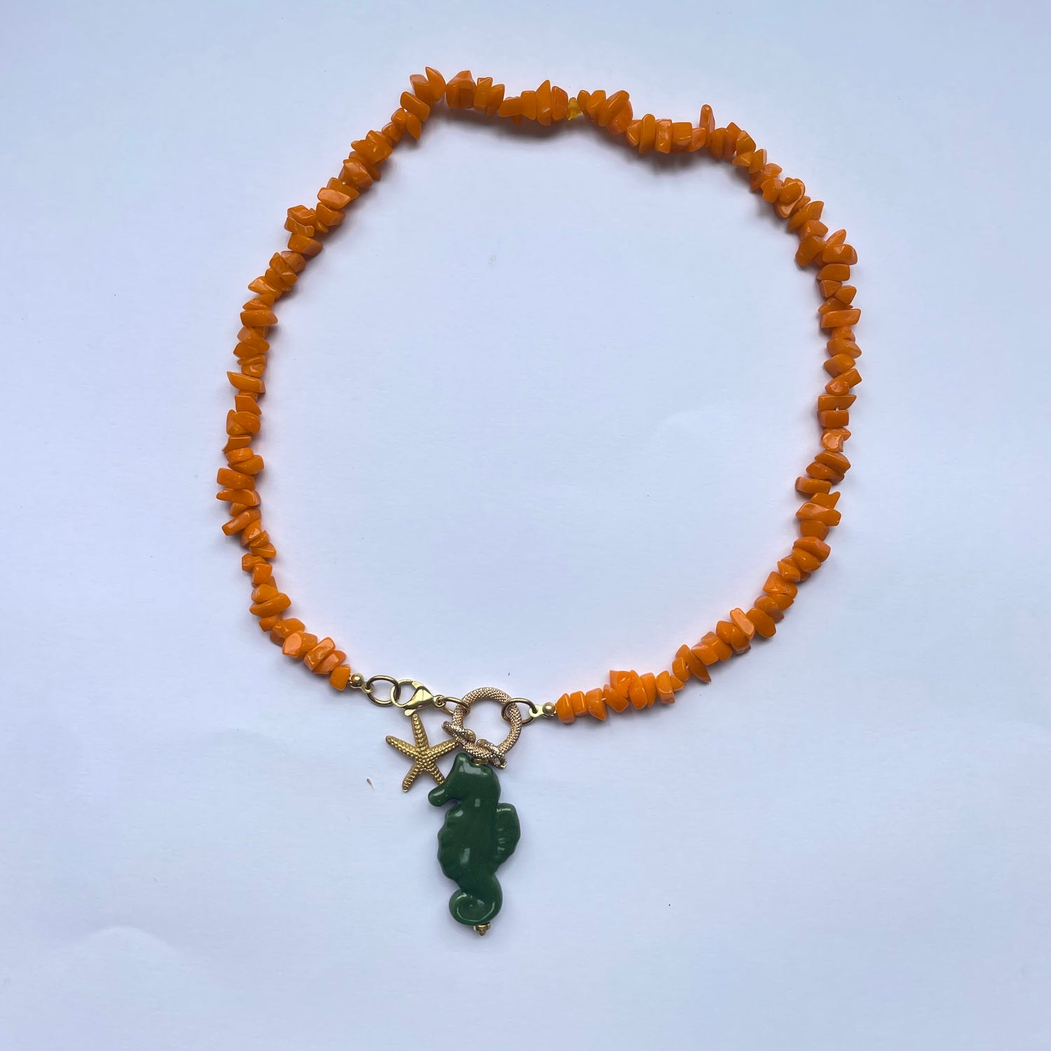 Collar corto de piedras naranjas y un caballito de mar verde de cerámica adornado con perla natural y estrella dorada Marardi