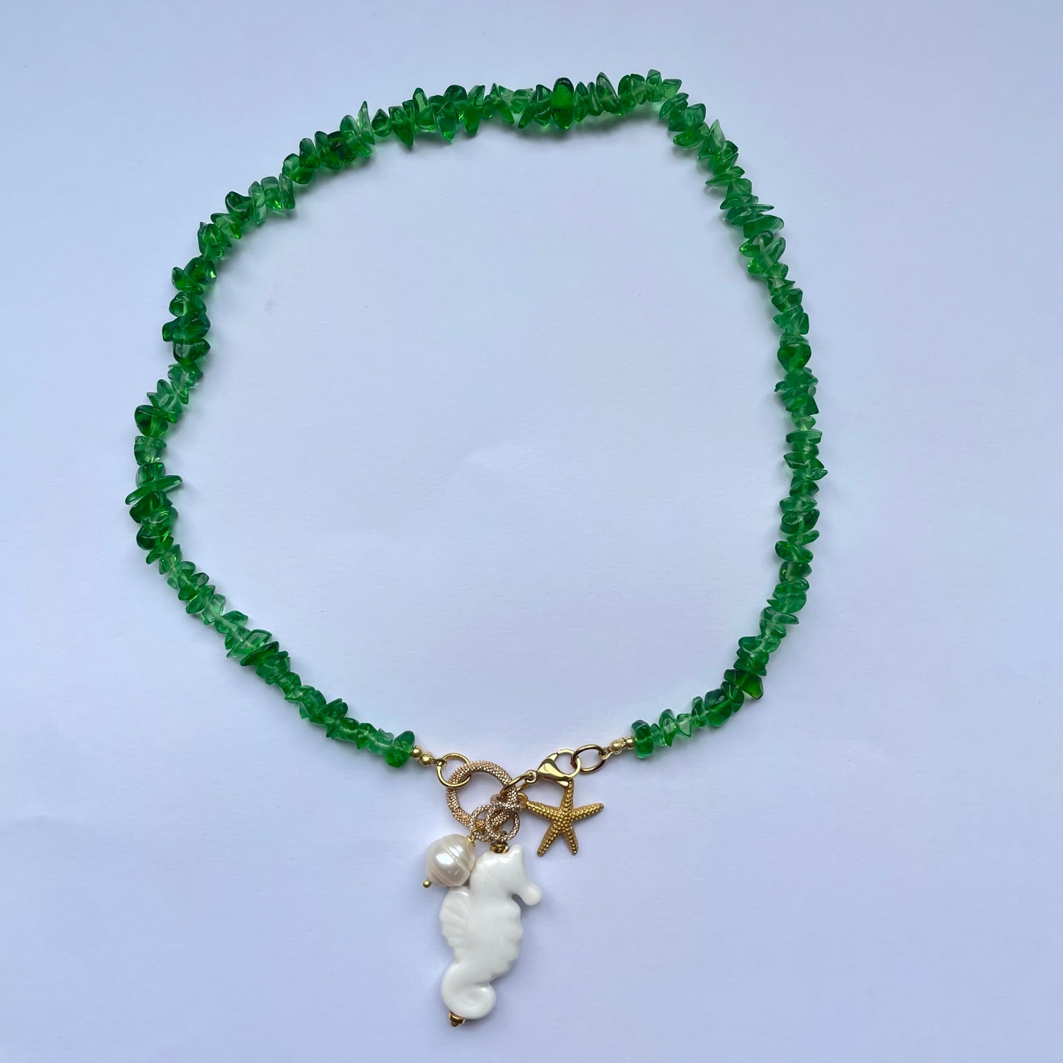 Collar corto de piedras verdes y un caballito de mar blanco de cerámica adornado con perla natural y estrella dorada Marardi.