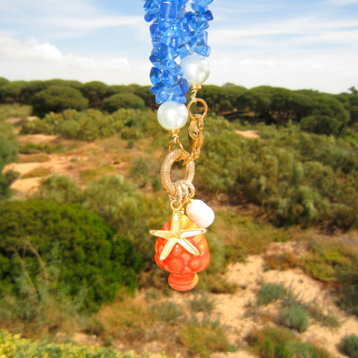 Collar corto de piedras azules y colgante de cerámica que es una piña naranja con una perla natural y estrella de marardi