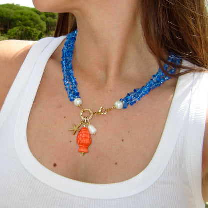 Collar corto de piedras azules y colgante de cerámica que es una piña naranja con una perla natural y estrella de marardi